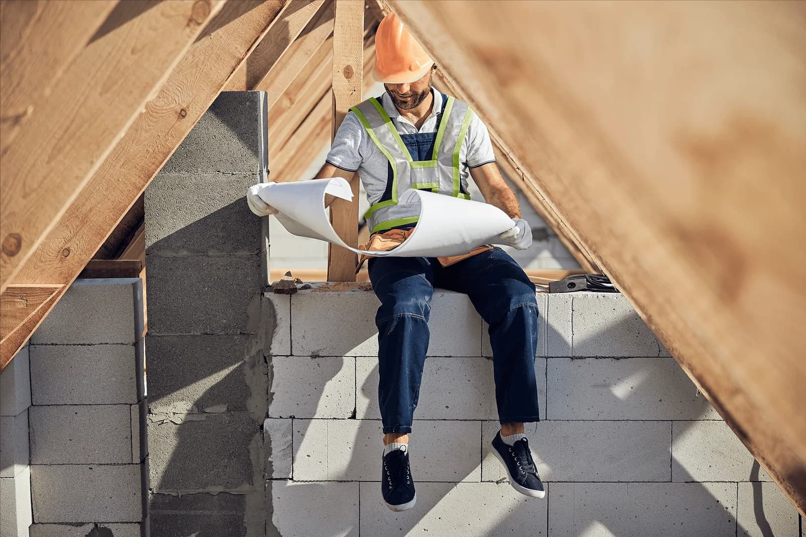 Worker reviewing drawings beneath exposed timber roof framing