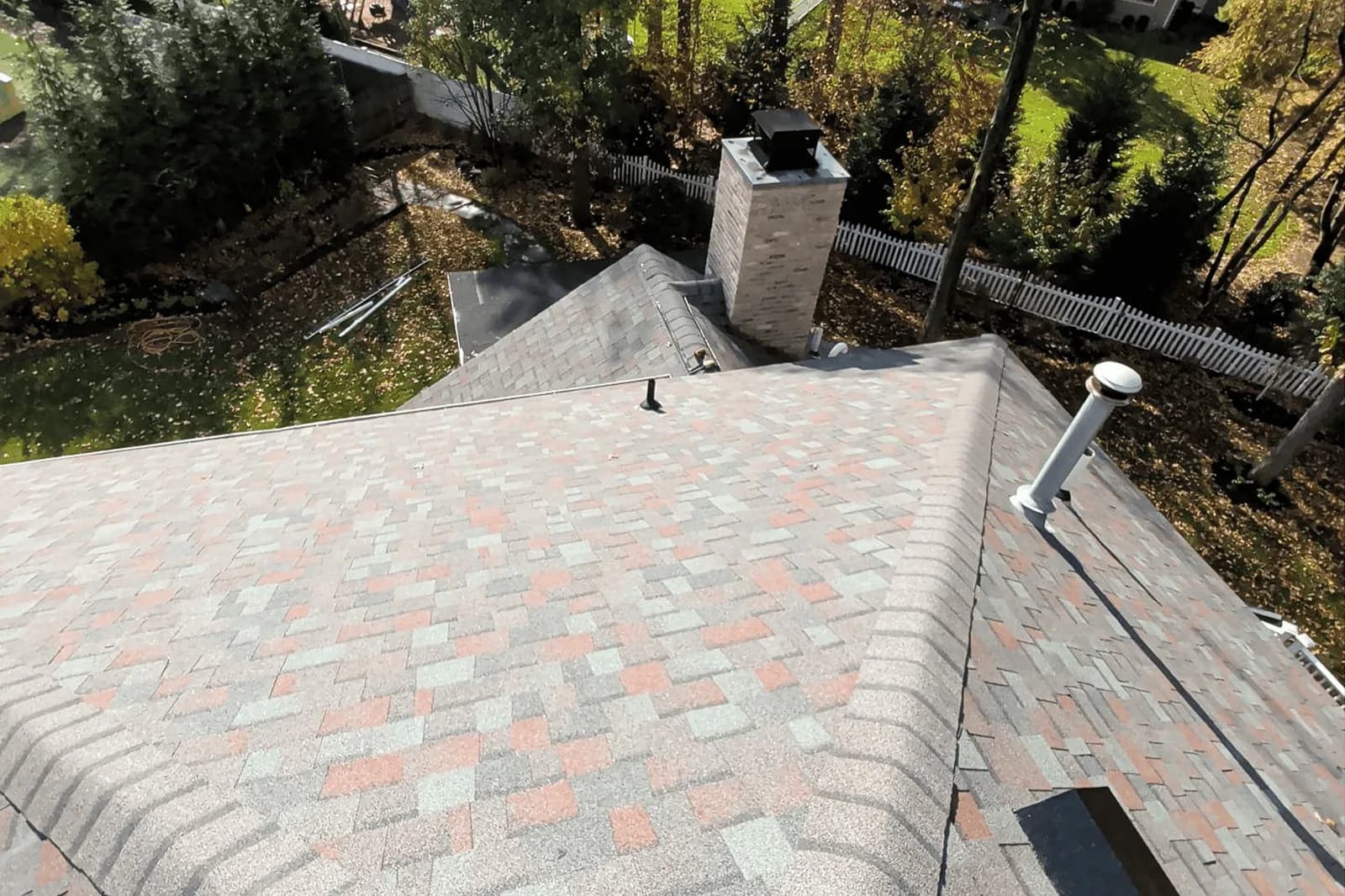 Masonry chimney with a metal cap where two shingle roof slopes meet