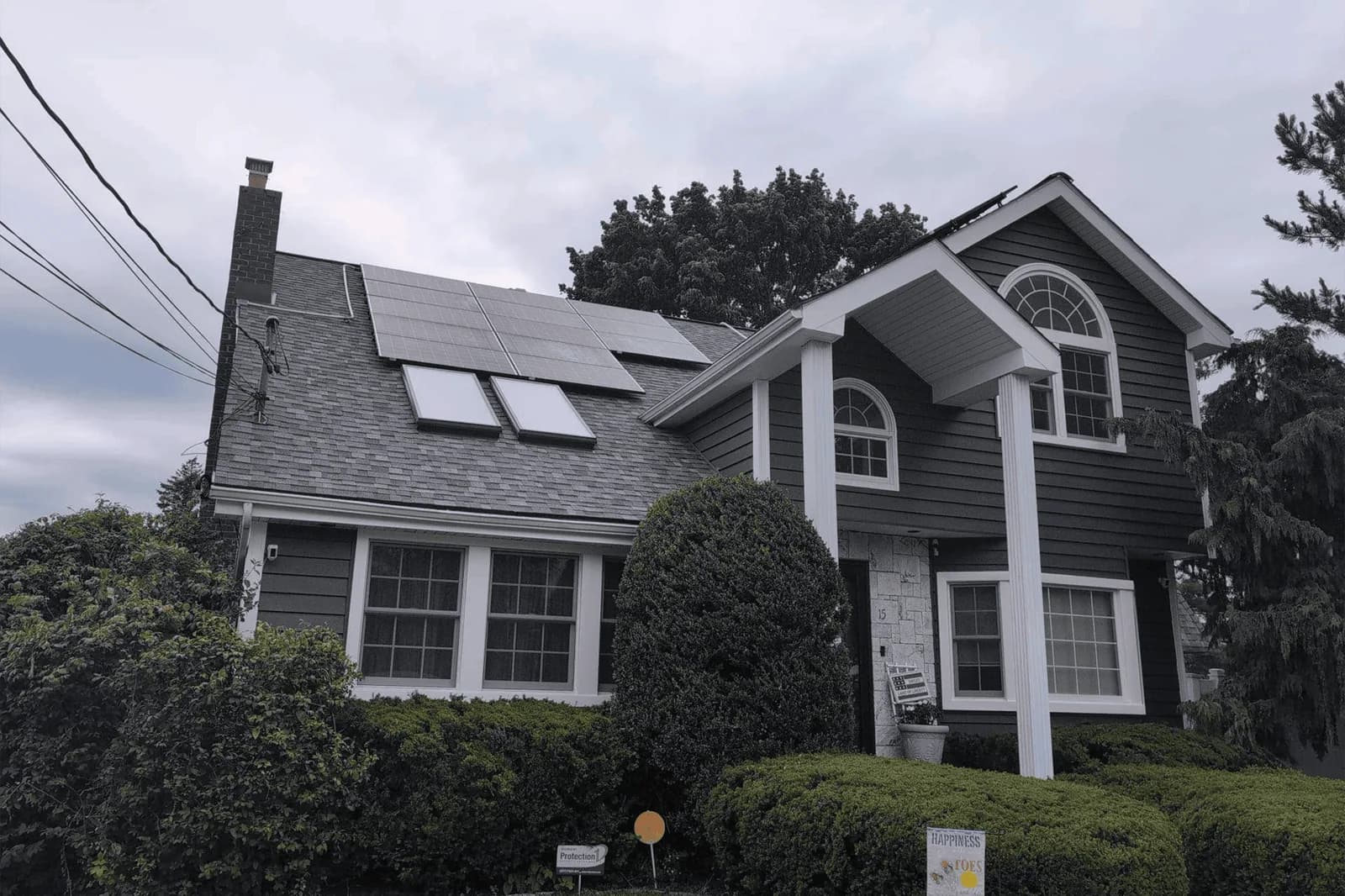 Gray-sided house with white trim, a tall chimney, and skylights in the roof