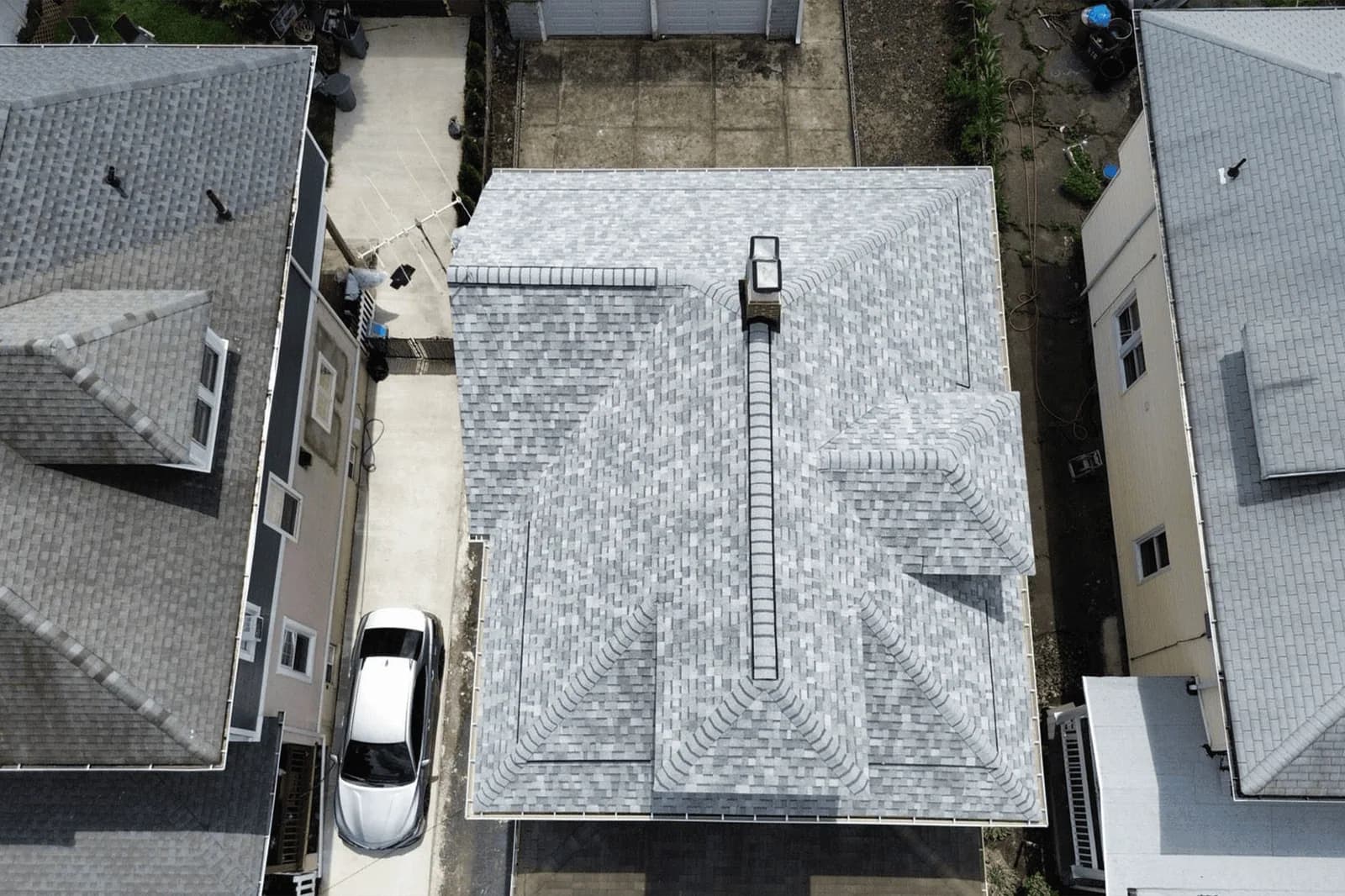 Overhead view of a gray shingle roof between neighboring houses