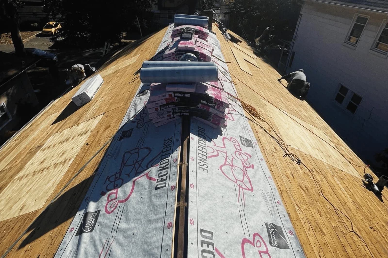 Exposed roof decking with underlayment and roofing materials along the ridge