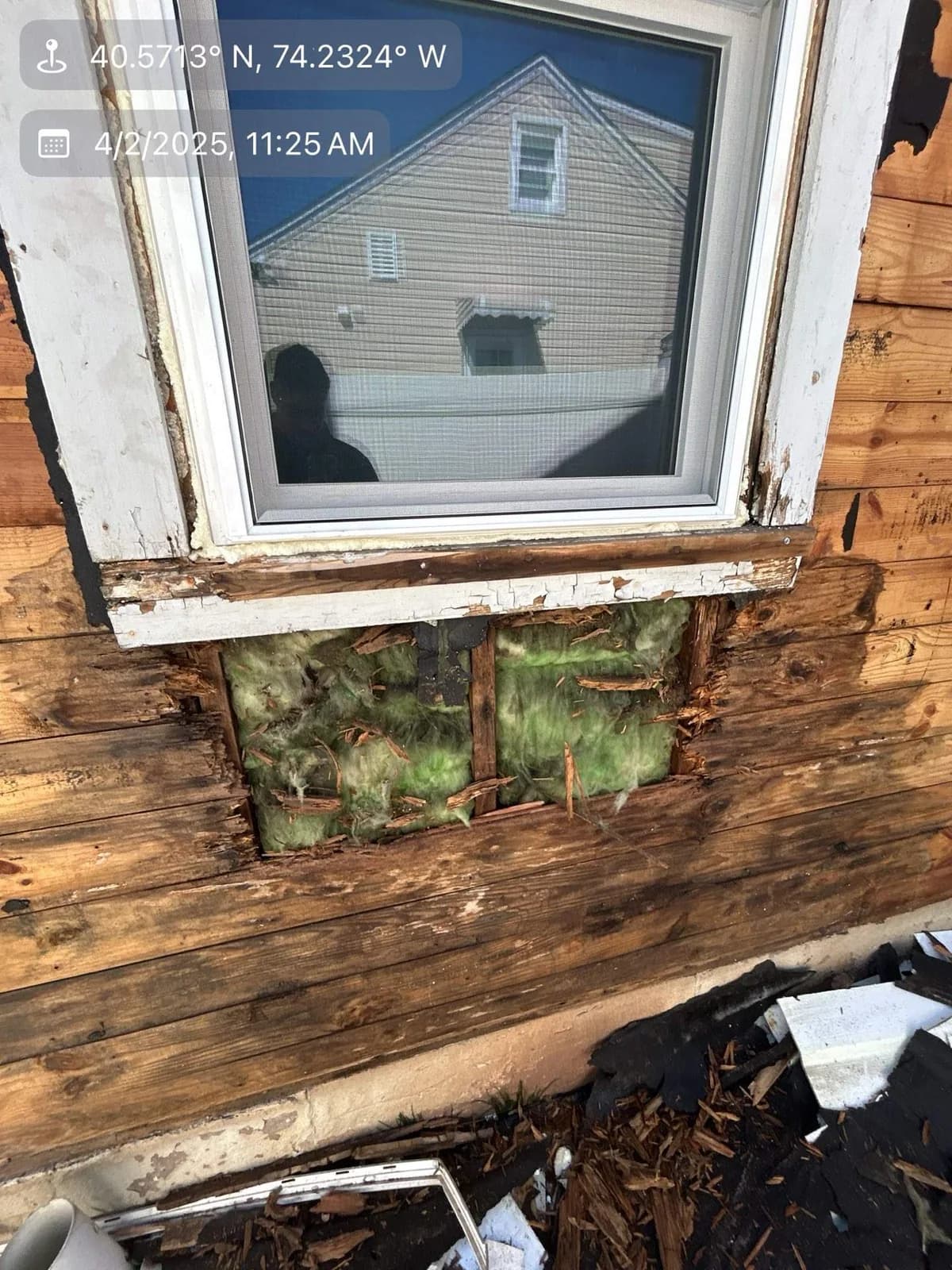 Exposed deteriorated sheathing and insulation beneath an exterior window