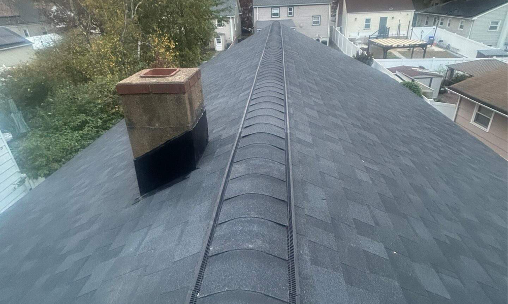 Completed residential asphalt shingle roof with ridge vent and chimney in New Jersey by Vesta Remodeling